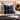 Harris Tweed Denim MacLeod cushion on a bed with an open book and glasses in a cozy bedroom setting.
