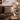 Cozy living room with a brown sofa, Harris Tweed Eriskay Bracken Herringbone cushion, candles, and a lamp.