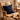 Wooden rocking chair with a Harris Tweed Black Watch Tartan cushion against a stone wall.