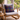 Cozy living room with a wooden armchair featuring a Harris Tweed Callanish Tartan cushion next to a small table with a cup and books.