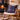 Wooden rocking chair with a Harris Tweed Callanish Tartan cushion in front of a fireplace.
