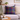 Harris Tweed Callanish Tartan cushion on a gray sofa with a coffee cup and books on a small table.