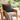 Wicker chair with a Harris Tweed Charcoal Herringbone cushion, set against a garden backdrop.