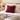 Bed with Harris Tweed Claret red cushion and beige bedding in a bedroom setting