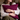 Woman holding a Harris Tweed Claret red cushion with a blurred background