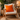 Wooden rocking chair with a Harris Tweed Clementine orange cushion in a cozy room.