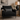 Black armchair with a Harris Tweed Grey Herringbone lumbar cushion in a living room setting.