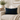 Black Watch Harris Tweed lumbar cushion on a beige sofa with a plant and books in the background