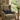 Beige armchair with a Harris Tweed Callanish Tartan cushion in a room with a window view of greenery.