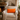 Cozy living room with a beige armchair featuring a Harris Tweed Clementine orange cushion a fireplace, and decorative elements.