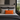 Bedroom with gray bedding and Harris Tweed Clementine orange cushion, framed picture on wall