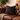 Brown leather sofa with a Harris Tweed Heather Glade cushion and blanket, next to a lamp and plant.