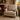 Beige armchair with a Harris Tweed Latte lumbar cushion and blanket in a cozy living room with a fireplace.