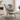Patterned armchair with a Harris Tweed Light Grey Marl lumbar cushion in a room with a bookshelf and window.