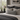 Neatly made bed with a Harris Tweed Light Grey Marl lumbar cushion in a bedroom setting.