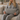 Woman holding a Harris Tweed Light Grey Marl lumbar cushion seated on a cosy sofa