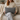 Woman holding a Harris Tweed Mid Grey Marl lumbar cushion on a beige couch in a cozy living room.