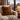 Harris Tweed Moss, Gingerbread & Wine cushion on a couch with a cityscape view through large windows.
