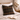Harris Tweed Oakwoods Tartan cushion on a bed with an open book and decorative vase in the background