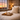 Cozy bedroom with sunset view, Harris Tweed Oatmeal cushion on the bed, lit candles, and a tray with a mug and book.