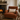Cozy living room with a brown armchair, fireplace, and Harris Tweed Oatmeal lumbar cushion.