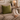 Person relaxing on a couch with a Harris Tweed Olive cushion, and warm lighting