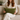 Woman holding a Harris Tweed Olive lumbar cushion on a couch in a cozy living room.
