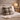 Harris Tweed Tarbert Herringbone cushion on a bed with an open book, lamp, and flowers in a room setting.