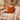 Cozy living room with a beige sofa, Harris Tweed Terracotta cushion, and decorative wreath on a stone wall.