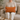 Woman sitting on a couch holding a Harris Tweed Terracotta lumbar cushion in a cozy living room.