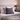 Bedroom with a bed featuring a Harris Tweed Thistle and Flint Wave cushion and a nightstand with a lamp.