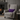 Gray armchair with a Harris Tweed Thistle lumbar cushion and blanket in a cozy living room setting.
