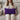 Woman holding a Harris Tweed Thistle lumbar cushion on a couch in a cozy living room setting