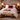 Cozy bedroom with stone wall, wooden bed, and red Harris Tweed Winterberry Tartan cushion