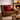 Brown leather armchair with a red Harris Tweed Winterberry Tartan cushion in a cozy living room with a fireplace.